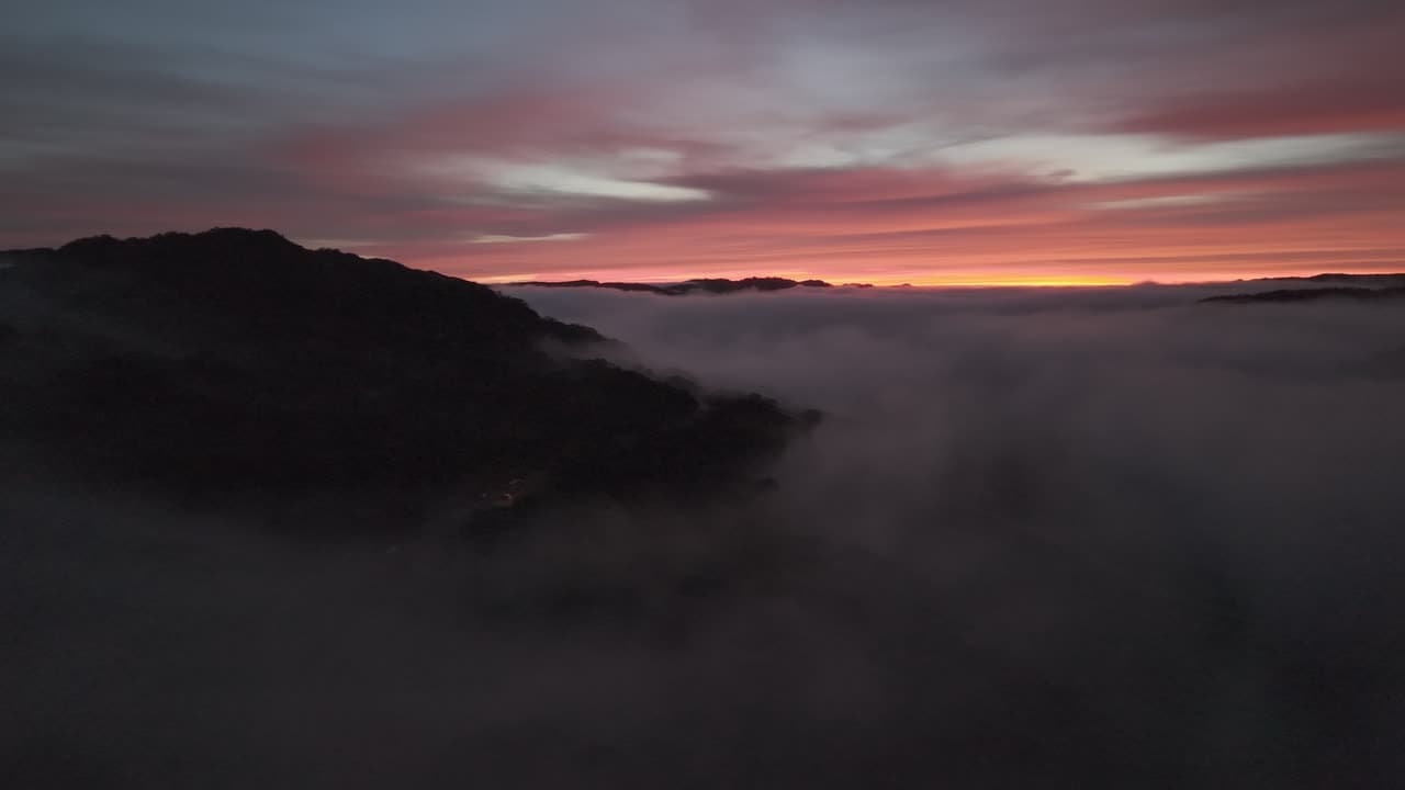 Sunrise over fog-filled valleys and ridgelines, captured from the air